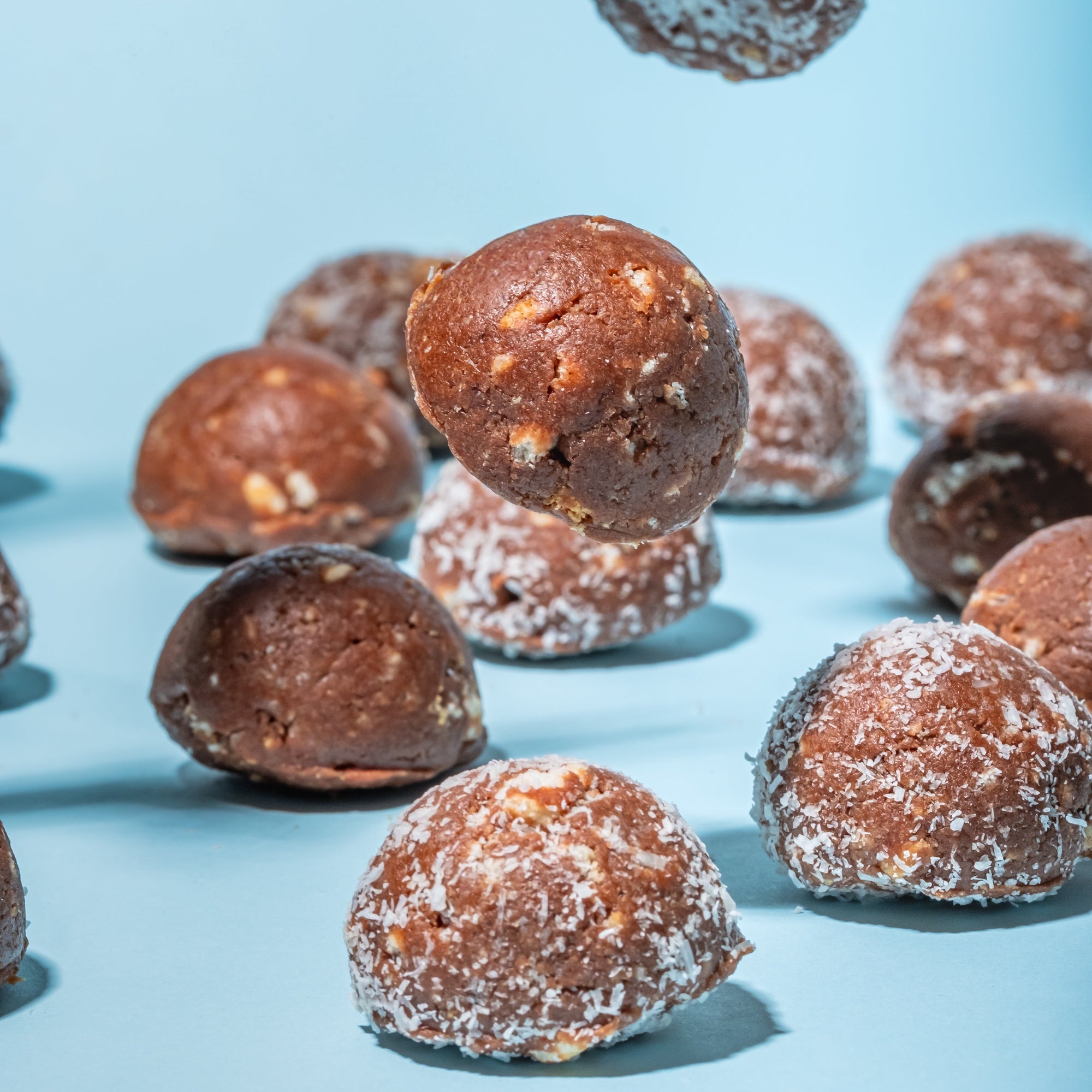 Chocolate truffles with a light dusting of cocoa powder on a blue background